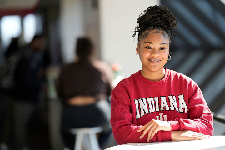 A female student wearing an Indiana sweatshirt sits at a table.